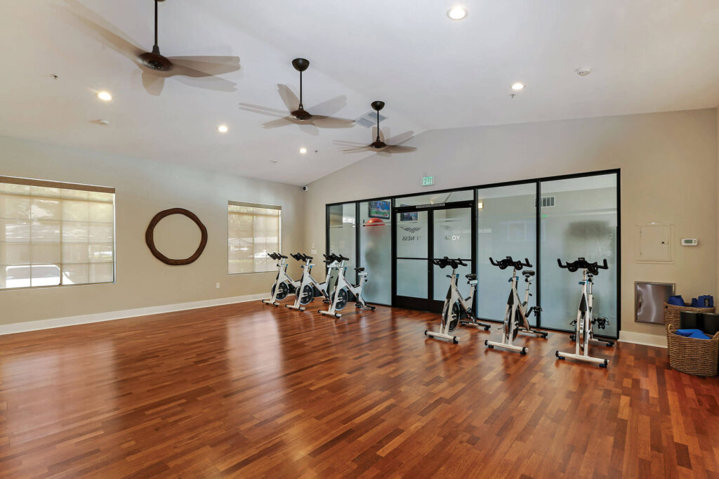 Indoor yoga and spin cycling fitness center with three overhead fans and yoga equipment