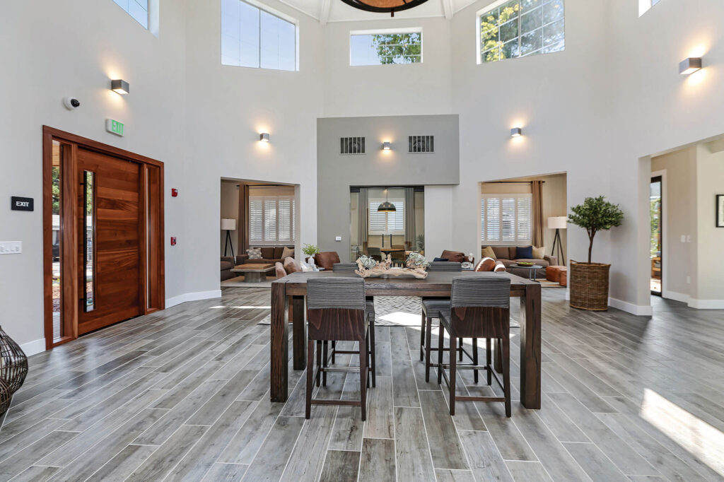 Leasing center with bar height center table and chairs, two rooms with sofa seating and a small conference space