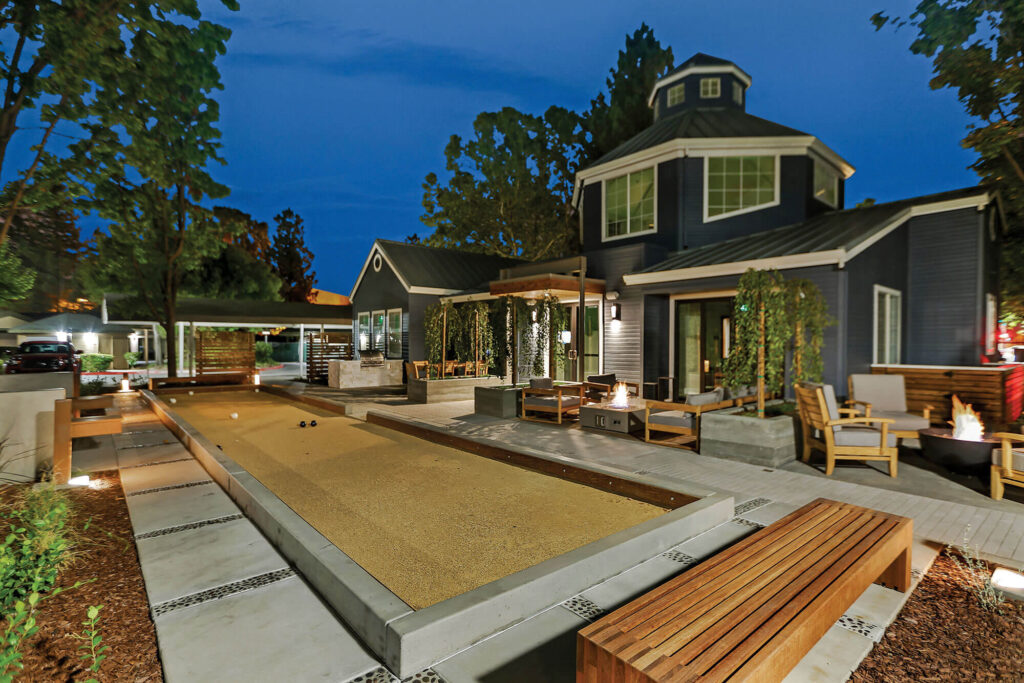Exterior view of blue leasing center building with outdoor seating, grilling, fire pits and Bocce Ball court