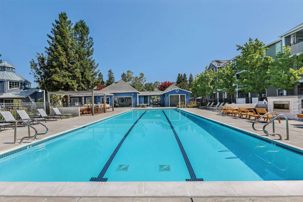 Swimming pool with covered bar height seating area, lounge chairs and outdoor fire pit