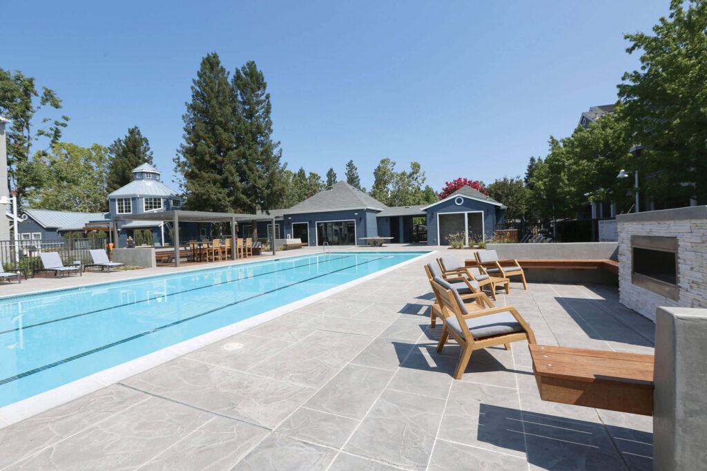 Swimming pool with tile patio and and lounge chair space with outdoor fire place