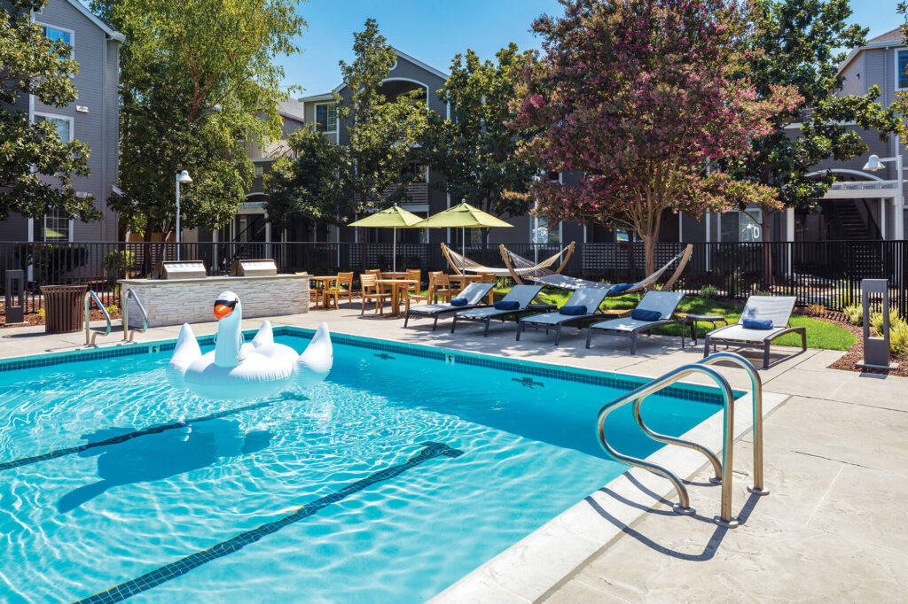 Swan floatation toy on swimming pool with hammock space, grilling and outdoor lounge chairs next to it