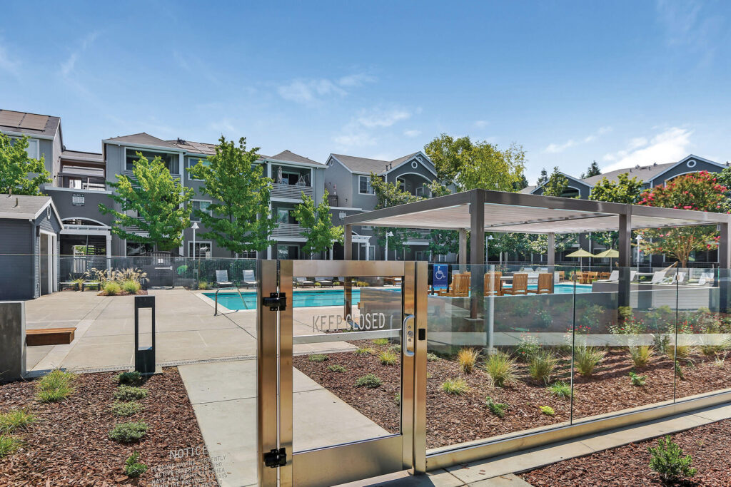 Glass fence around swimming pool and patio space with shaded canopy on top of bar height seating
