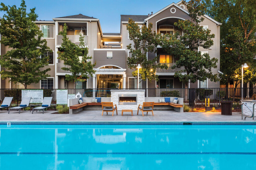 Outdoor fireplace with benches and armchair seats next to swimming pool
