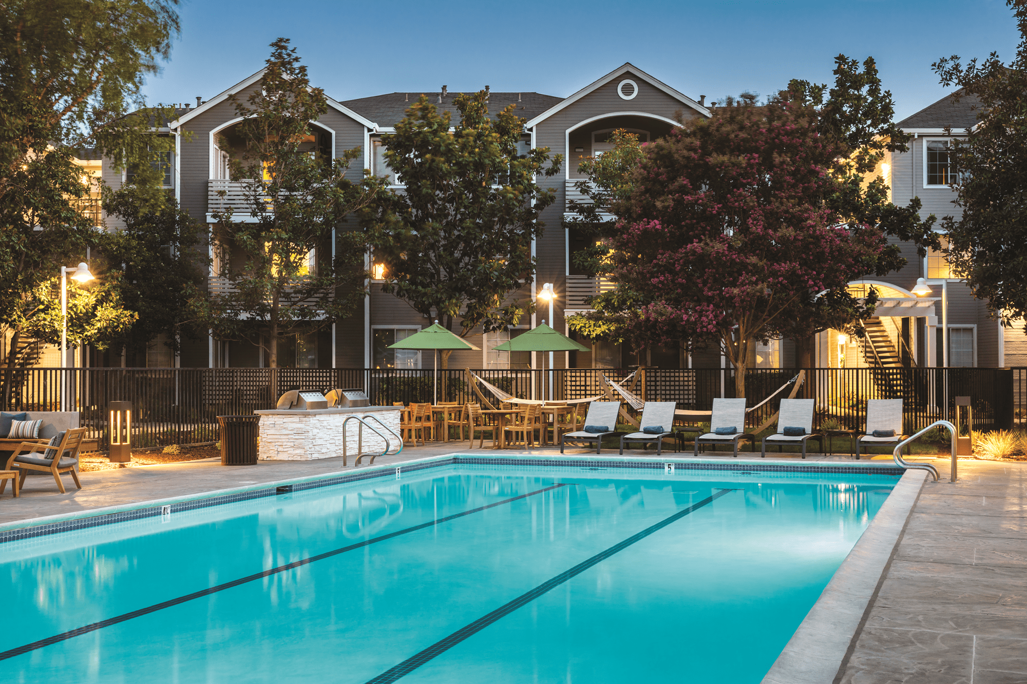 Swimming pool with lounge chairs, grilling station, hammock space and outdoor umbrella-covered dining spaces